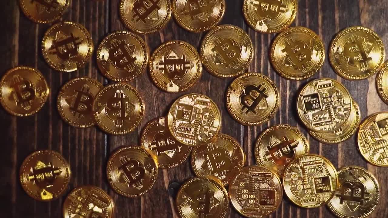 video cinematográfico de monedas de criptomoneda bitcoin en una mesa de madera bellamente iluminada