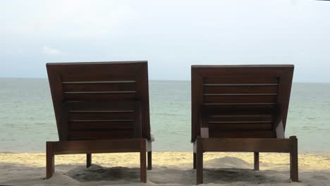 View-from-behind-of-two-sunbeds-or-beach-beds-on-the-sandy-beach-of-Thailand,-no-people