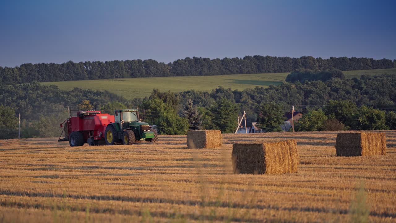 Square bales and a tractor on the field. agricultural machine pressing dry hay on the natural rural landscape in summer.