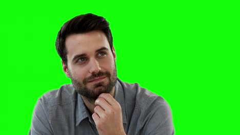 Thoughtful-man-sitting-against-green-background