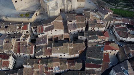4k aerial drone shot flying over medieval village with narrow streets, church, and castle in spain