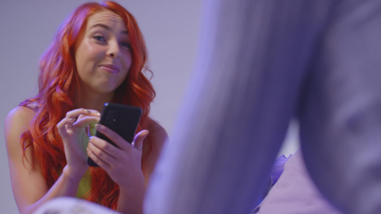 fotografía de estudio de cerca de amigos jóvenes de la generación z sentados en el sofá hablando y compartiendo publicaciones en las redes sociales en teléfonos móviles 11