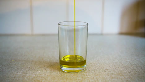 cooking oil being drizzledinto glass on kitchen bench