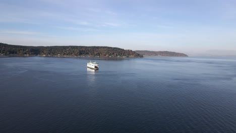 Wide-angle-of-a-bright-white-ferry-crossing-a-waterway,-calm-blue-water,-aerial-approach