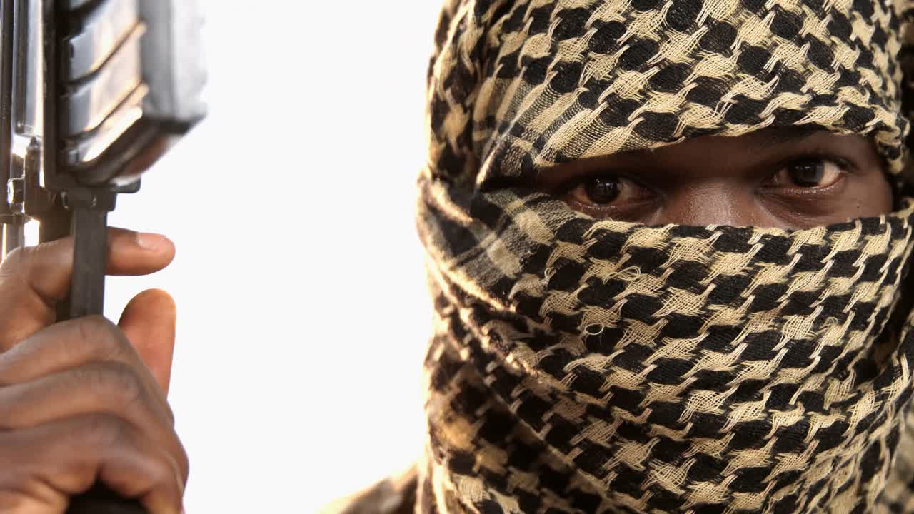 Terrorist holding machine gun against white background