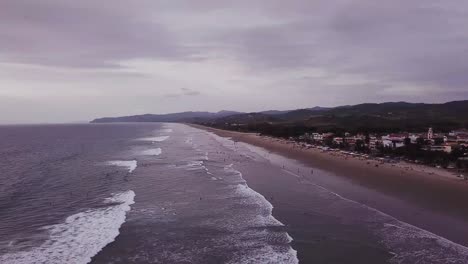 Menschen-Am-Welligen-Strand-In-Olon,-Ecuador-An-Einem-Bewölkten-Tag---Luftdrohne