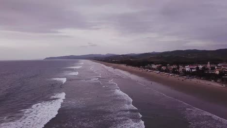 gente en la playa ondulada en olon, ecuador en un día nublado - drone aéreo