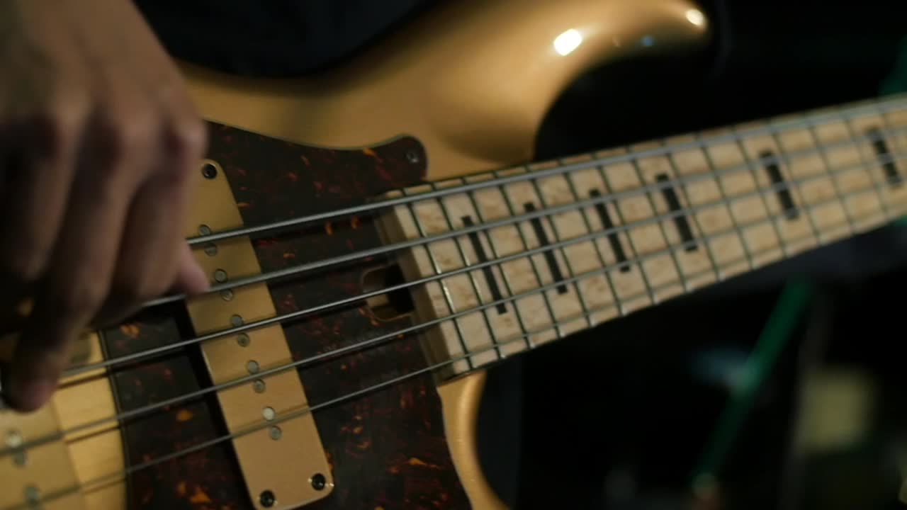 Bass guitar being played with colored stage lights lighting background in close up and slow motion