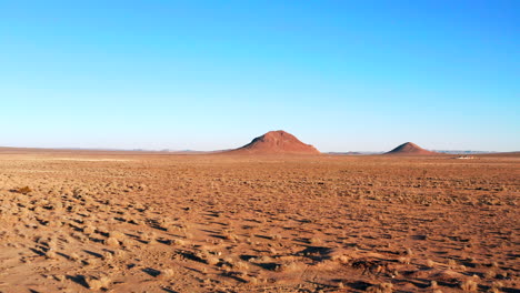 pull back aerial view of a cone-shaped volcanic mountain in the great mojave desert landscape