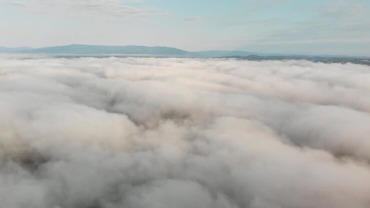 A mesmerizing aerial view soaring above the clouds with distant hills creating a stunning and serene landscape