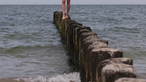 Fröhliche-Frau,-Die-Auf-Einem-Holzscheit-Läuft-Und-Ins-Wasser-Fällt,-Statische-Weitwinkelaufnahme