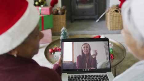 Diverse-senior-female-friends-using-laptop-for-christmas-video-call-with-happy-woman-on-screen