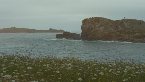 large rock face extends into the sea with person in the distance