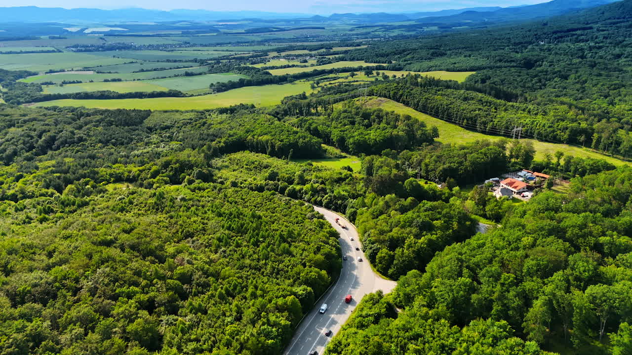 Vast beautiful green landscape in summer. Footage above the highway crossing the picturesque forest. Top view.