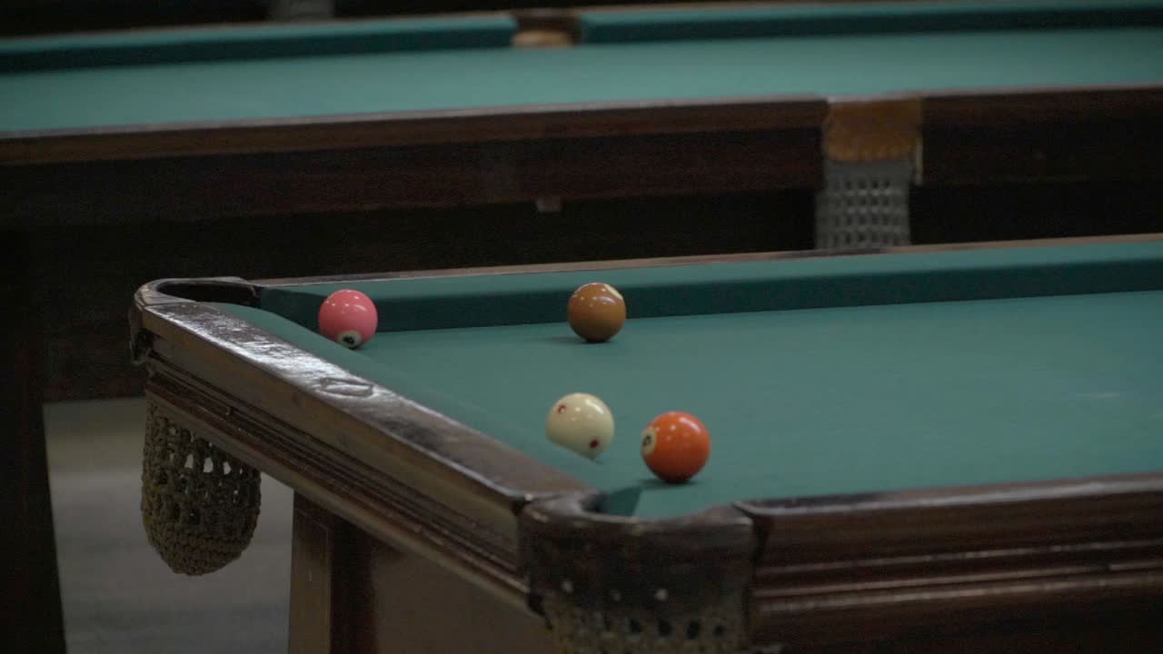 Slow-motion view of a ball pink 4-ball pushed into a corner pocket during a pool game