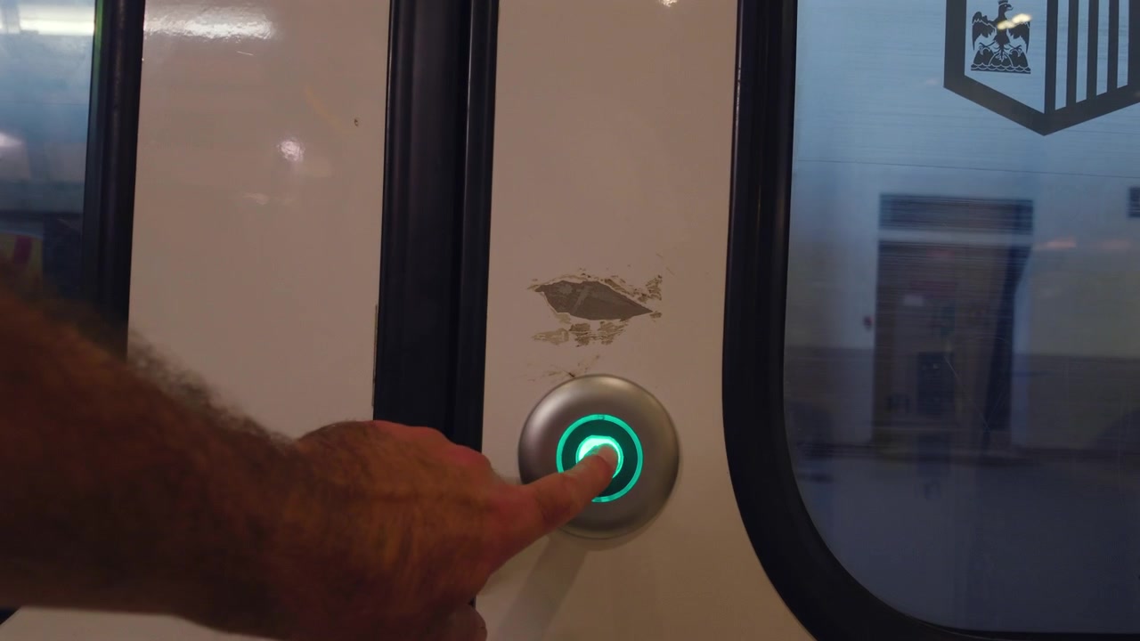 Close-up of a train carriage door with a lit green release button, Cannes, France