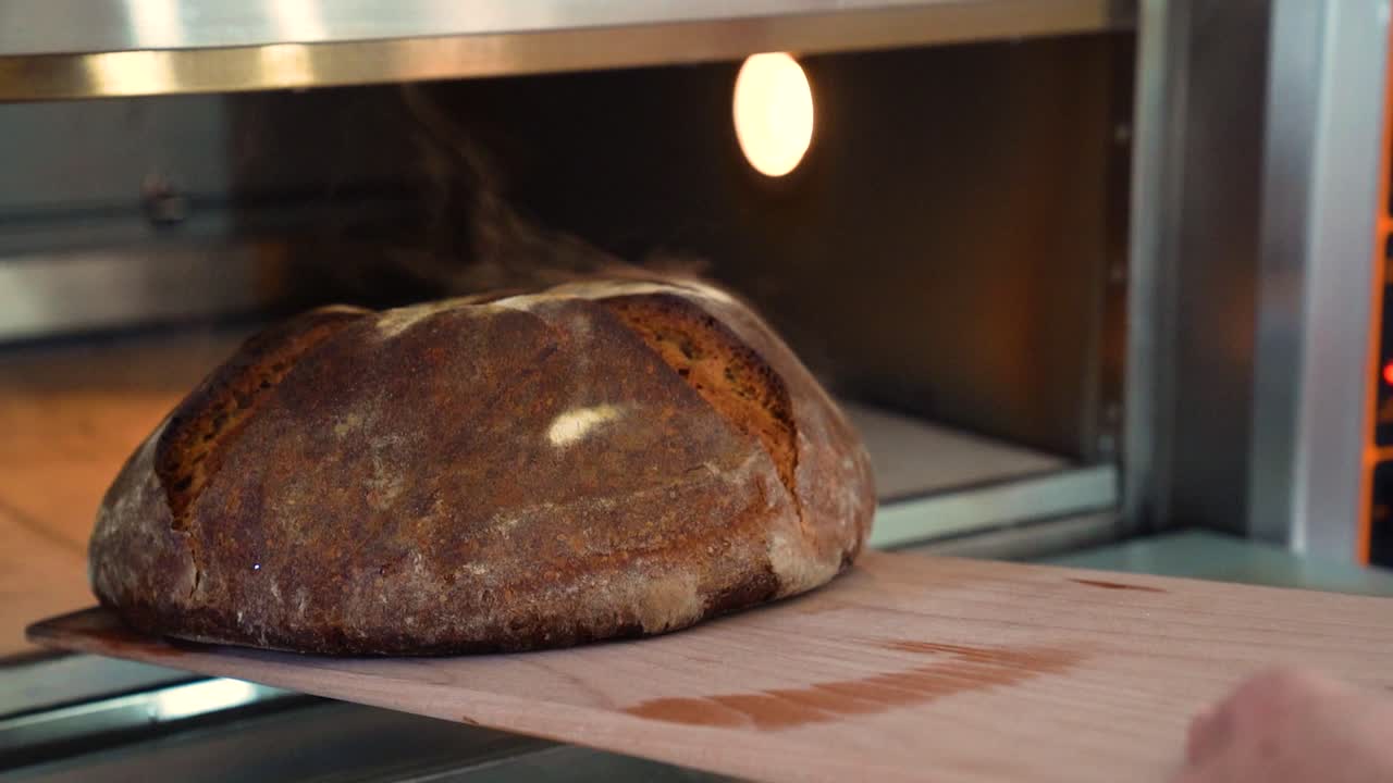 Freshly baked bread is being taken out of a hot oven