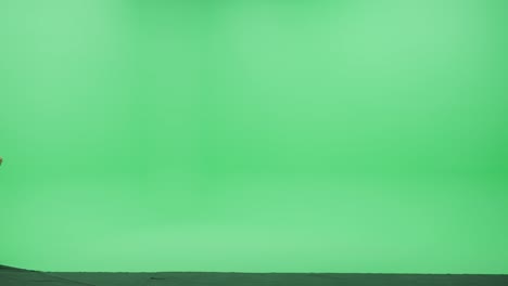 pantalla verde chroma clave estudio: joven guapo con ropa casual elegante baila a través de la habitación