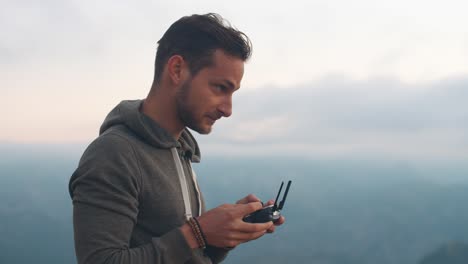 4K-Zeitlupenaufnahmen-Eines-Mannes,-Der-Seine-Drohne-Mit-Einem-Controller-In-Der-Hand-Fliegt