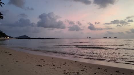 The-tranquility-of-Koh-Samui's-serene-beach-in-Thailand,-where-gentle-waves-caress-the-shore-against-a-backdrop-of-soft-clouds-and-the-warm-hues-of-a-sunset,-concept-of-travel-and-vacation