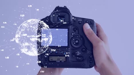 Globe-of-network-of-connections-spinning-against-close-up-of-hand-holding-a-digital-camera