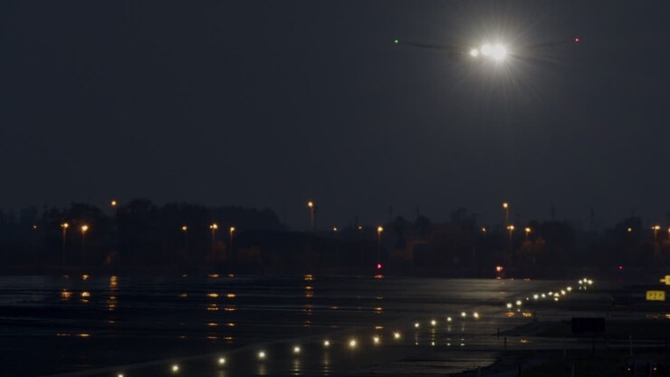Aereo che atterra di notte su una pista bagnata
