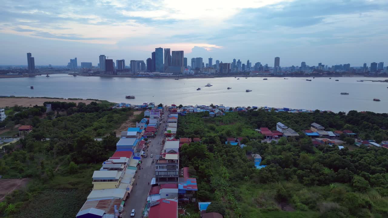 colorful houses and the Phnom Penh skyline reflecting on the Mekong River at evening. Tremendous aerial view flight wide orbit overview drone