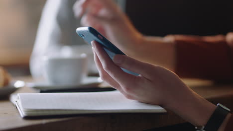 close up business woman hands using smartphone in cafe drinking coffee texting reading email messages networking on mobile phone internet connection