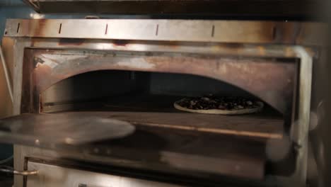 man cooking pizza in the kitchen of restaurant