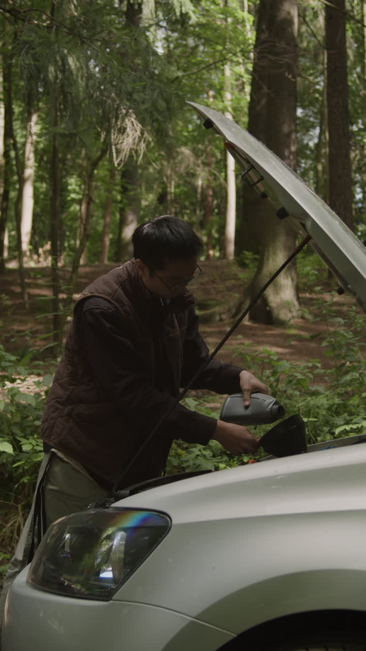 Man Maintaining Car in Forest