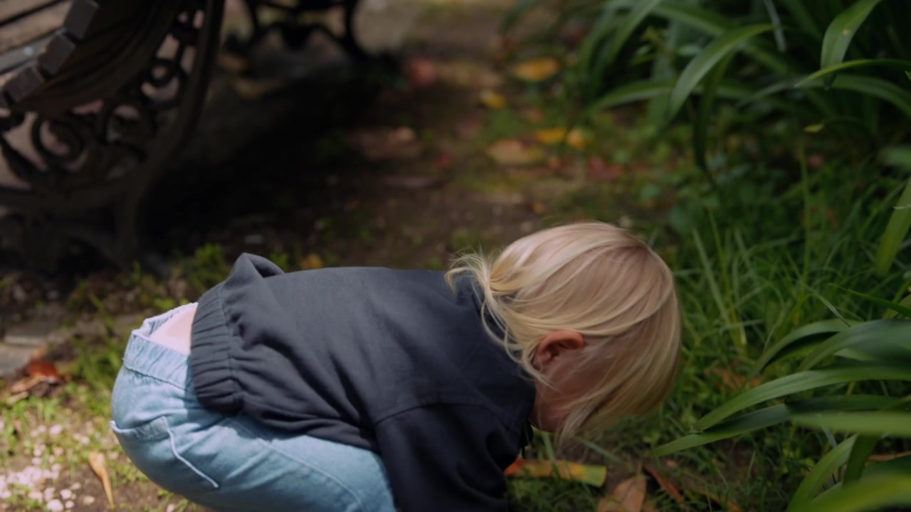 Blondes Kleinkind spielt und gestikuliert in einem Park