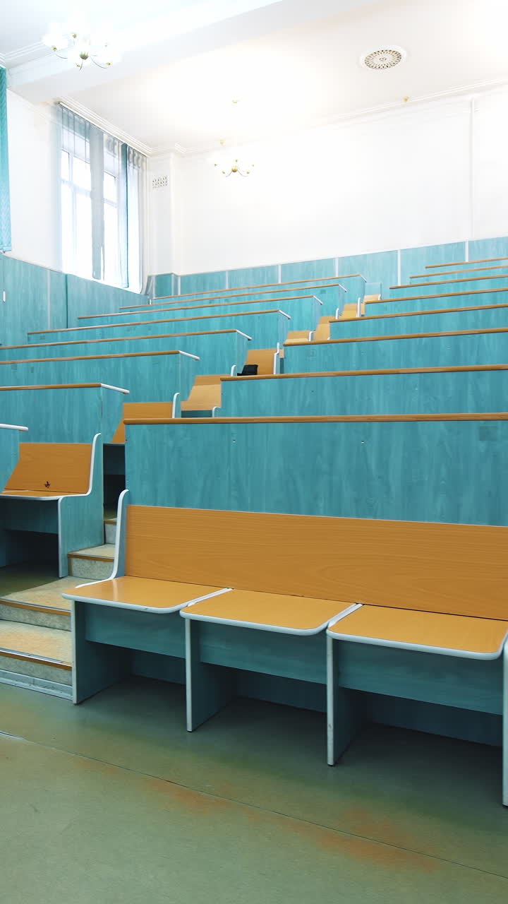 Comfortable classroom without students. Empty auditorium with wooden desks in blue color. Light lecture hall in the University. Vertical video