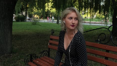 wonderful young girl sitting on a park bench and listening to music