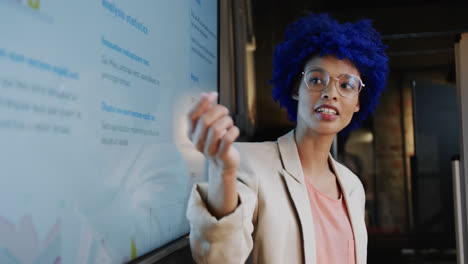 biracial casual businesswoman with blue afro making presentation in office, slow motion