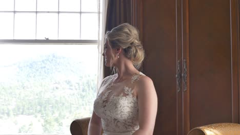 blonde bride sitting on hotel sofa turns her head and looks out the window