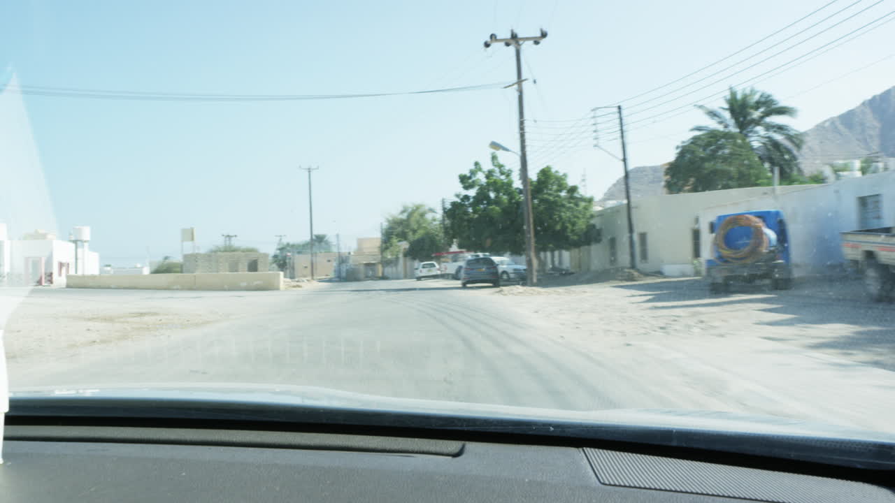 Driving in the streets of a town in Oman heading to Wadi Shab canyon, wide shot