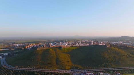 Toma-Aérea-Amplia-De-La-Ciudad-De-Elvas-En-La-Cima-De-La-Montaña-Durante-El-Día-Soleado-Con-Cielo-Azul-Por-La-Noche,-Portugal