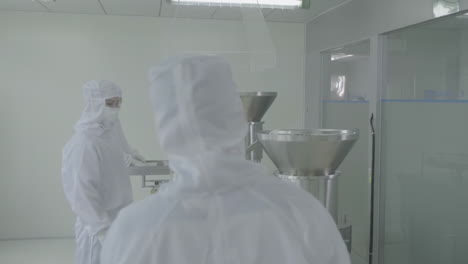 scientists or technicians in protective gear managing production line at a pharmaceutical manufacturing facility in sterile conditions