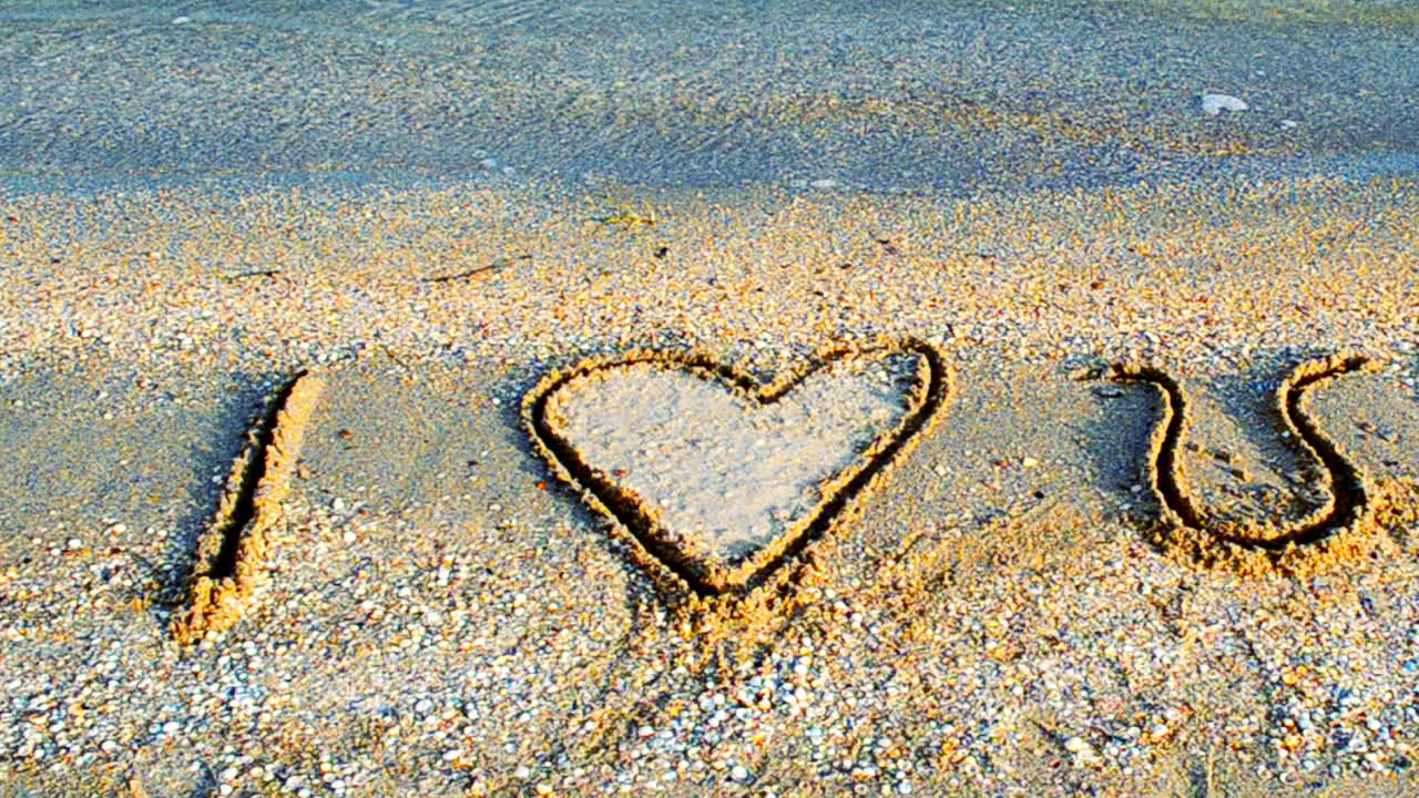Scritta sulla sabbia. Ti amo. Ripresa sulla spiaggia.