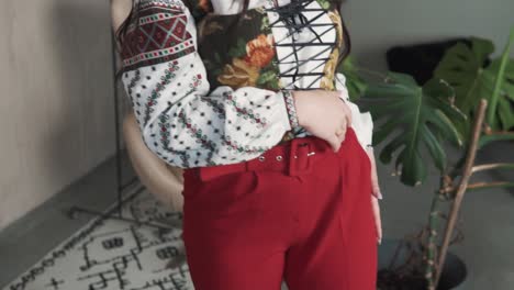 una joven bonita baila con una sonrisa vestida con una camisa y un corsé ucranianos auténticos bordados de moda