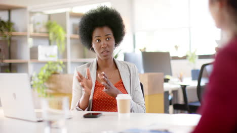 Diverse-female-creative-colleagues-in-discussion-using-laptop-in-office,-slow-motion