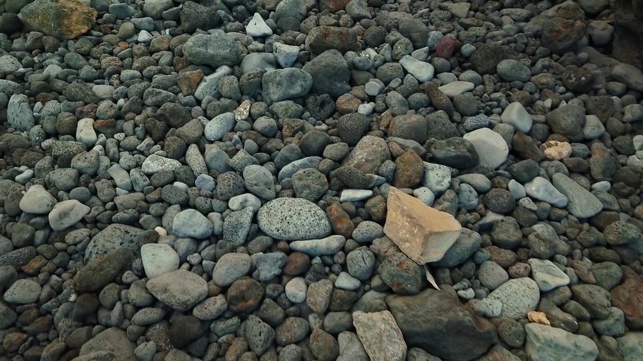 Vista de cerca de rocas volcánicas y guijarros que cubren la superficie de una playa natural