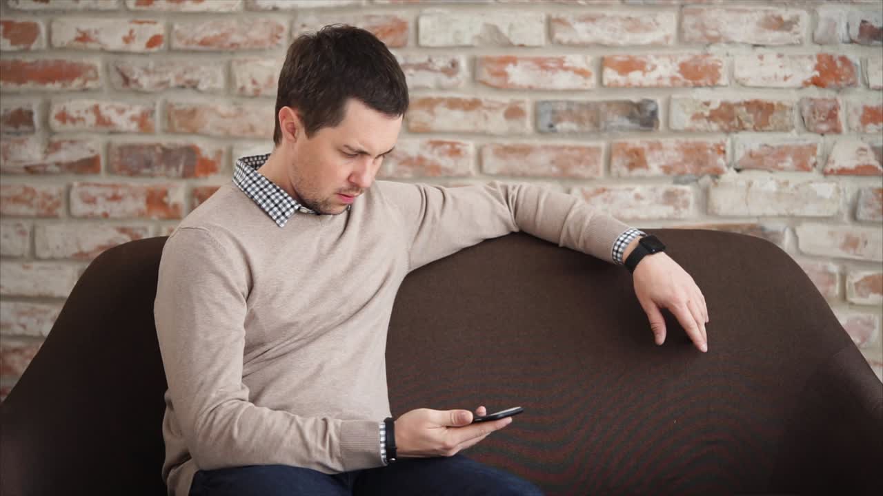 소파에서 스마트폰을 사용하는 남자