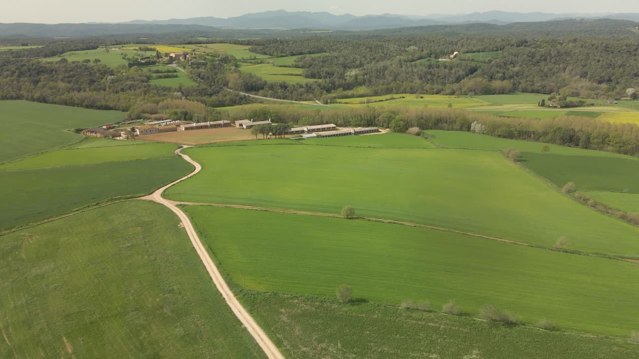 vuelo sobre una masía en la costa brava en girona verde campo cultivado y montañas amarillas en el fondo