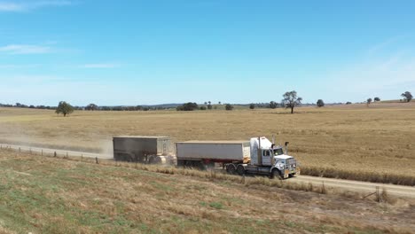 Una-Excelente-Toma-Aérea-De-Un-Camión-De-Doce-Ruedas-Remolcando-Un-Vehículo-Detrás-De-él-En-El-Campo-De-Parkes,-Nueva-Gales-Del-Sur,-Australia