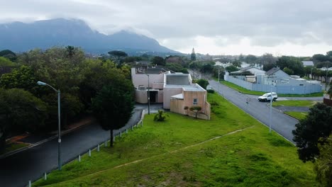 a drone shot revealing the suburb of meadowridge in cape town, with mountains and mist in the background