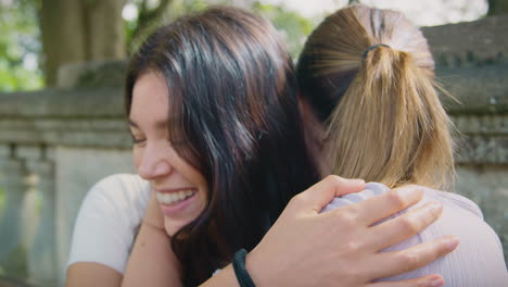 same sex female couple sightseeing around oxford uk sitting on bench and hugging