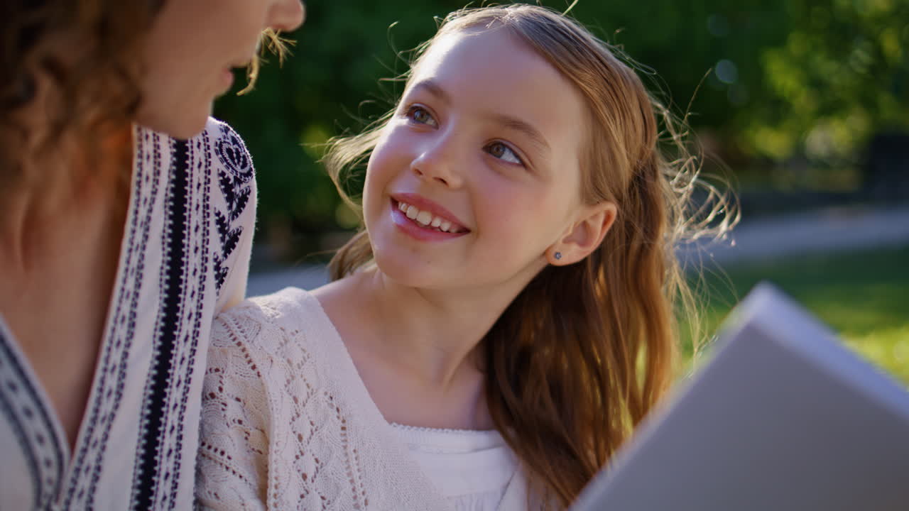 Little child reading fairytale for mom in park closeup. Parent kid enjoying book