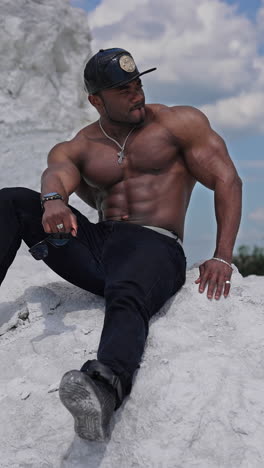 bodybuilder with naked torso outdoor. handsome athlete man showing muscles on the rocky mountain. vertical video