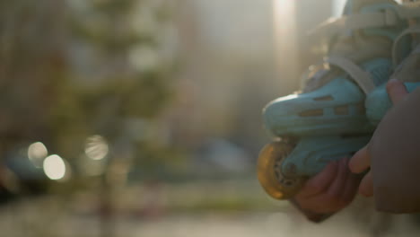 close-up shot of a girl's hand holding a skateboard while walking through a sunlit park. the scene focuses on the skateboard and hand, with the background softly blurred